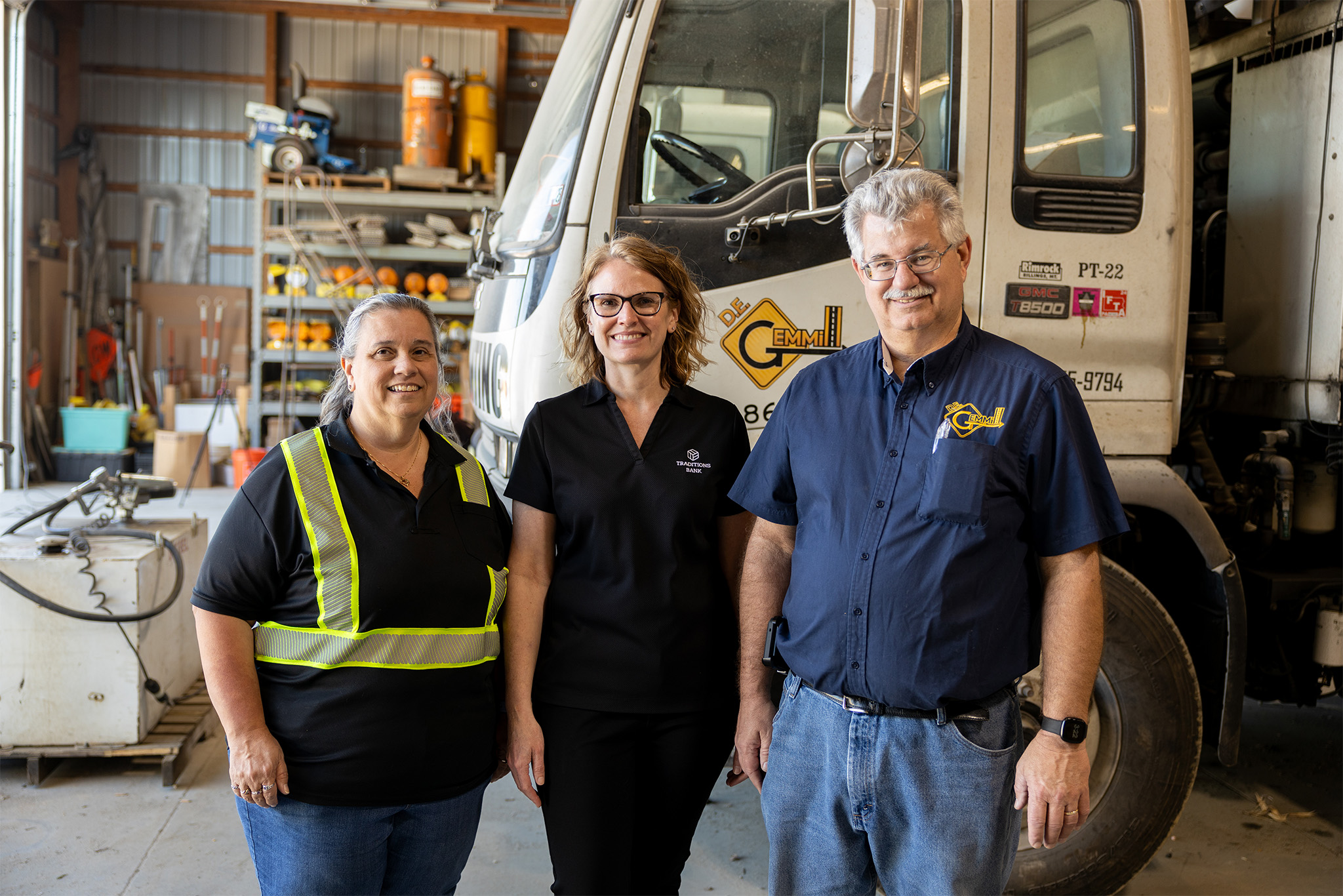 husband and wife business owner smiling alongside a female banker at their business